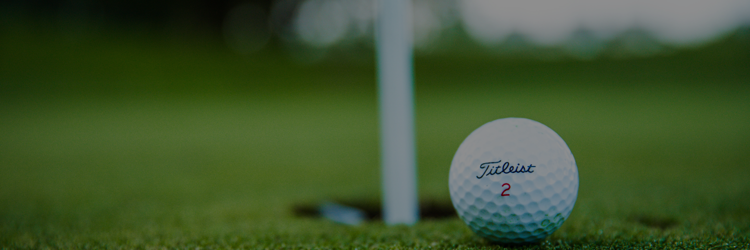 A golf ball next to a golf flag